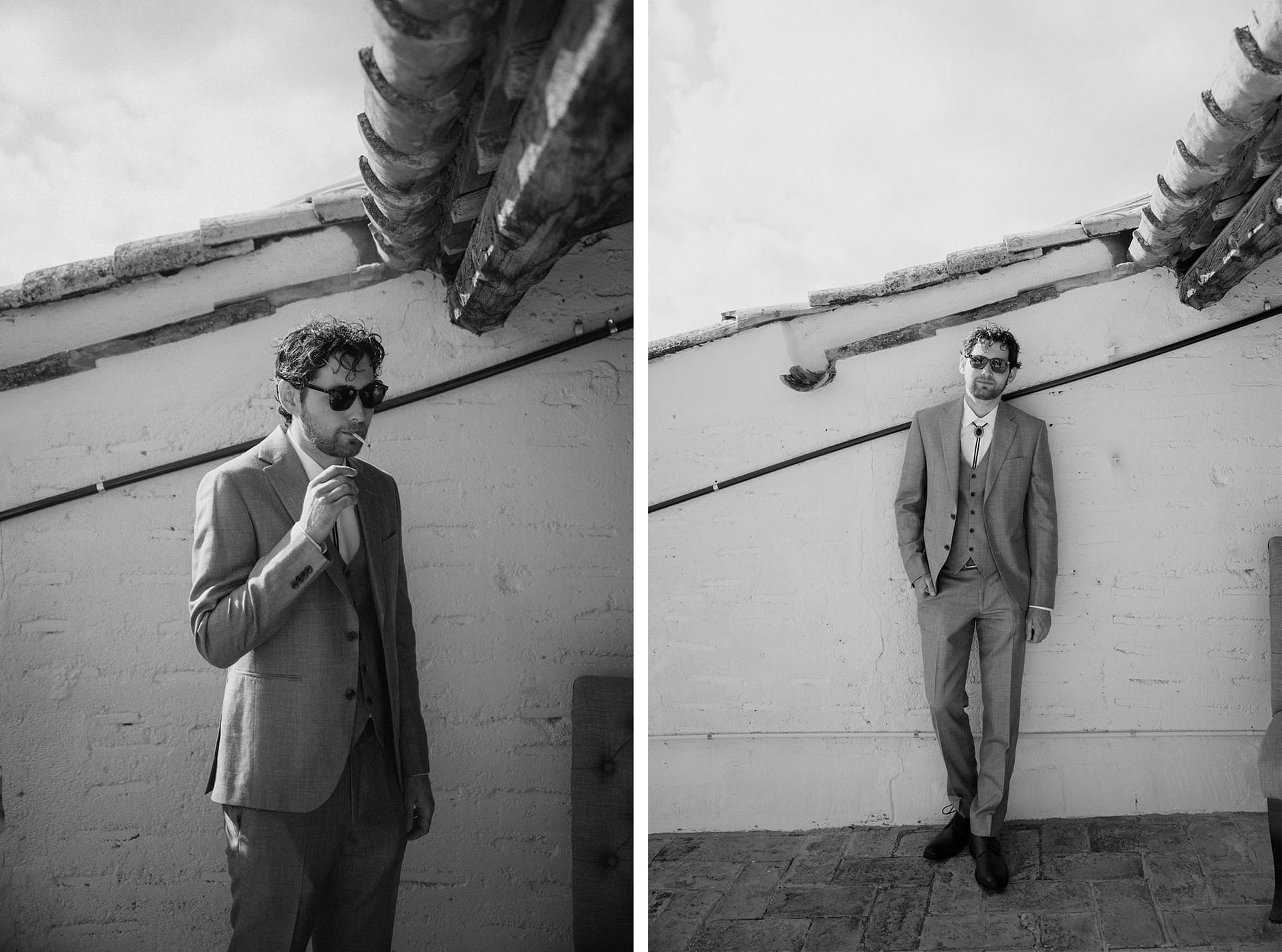 Groom in sunglasses and suit smokes cigarette, then poses against wall. - Barcelona Wedding Photographer