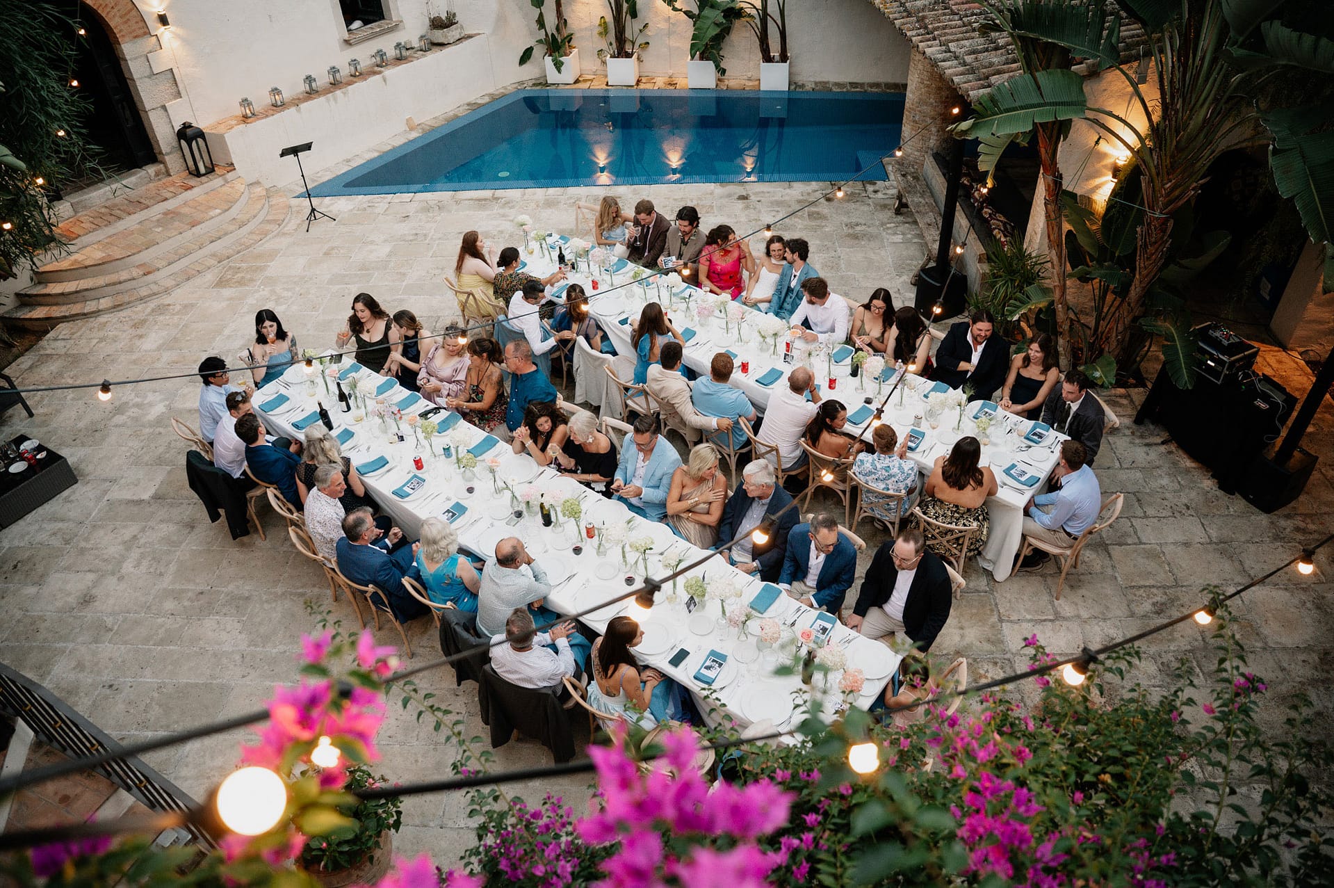 Elegant outdoor wedding reception with guests dining at long tables by a pool. - Intimate Wedding at Masia Victoria