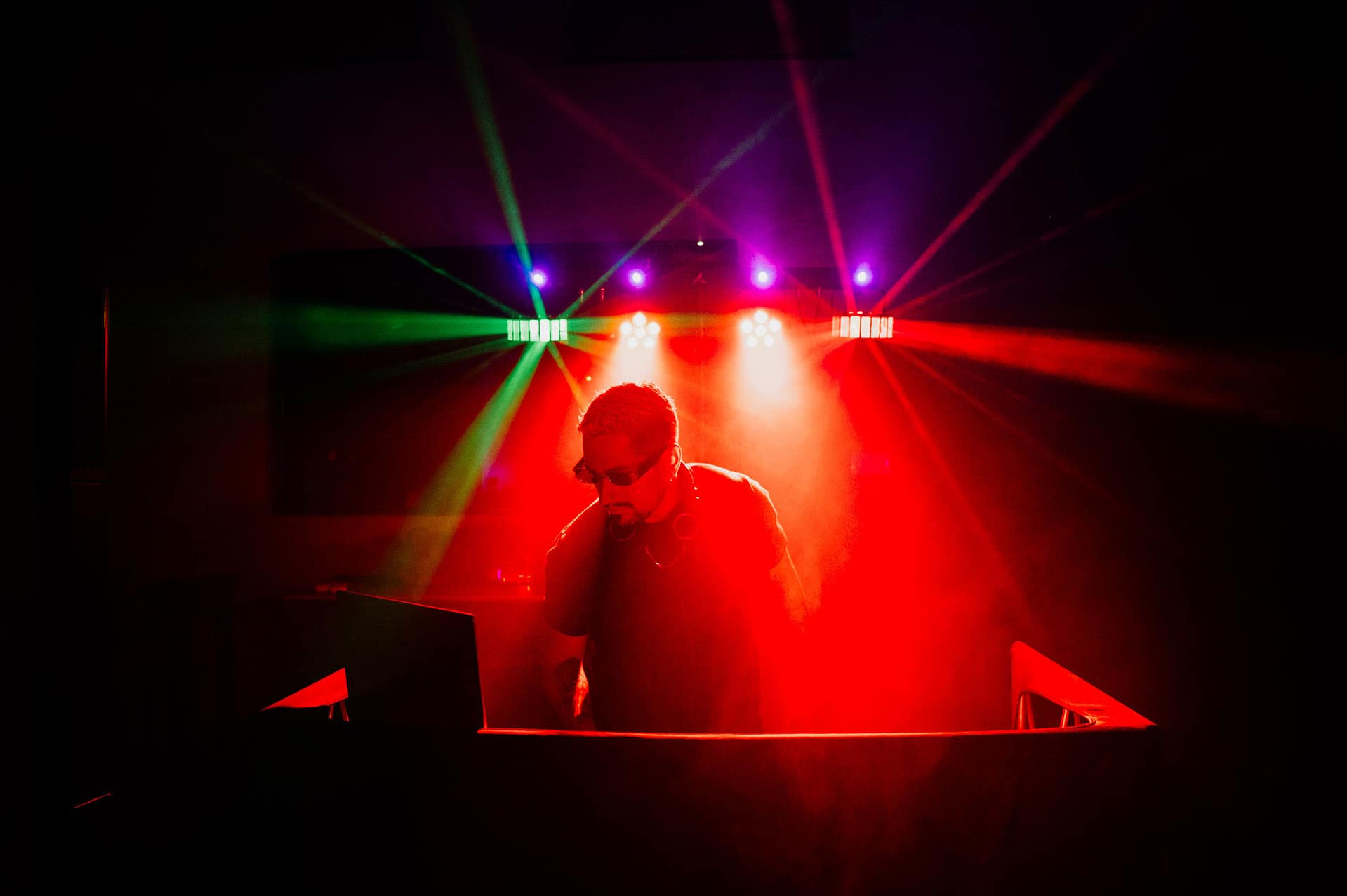 DJ in silhouette illuminated by red and green stage lights - Barcelona Wedding Photographer