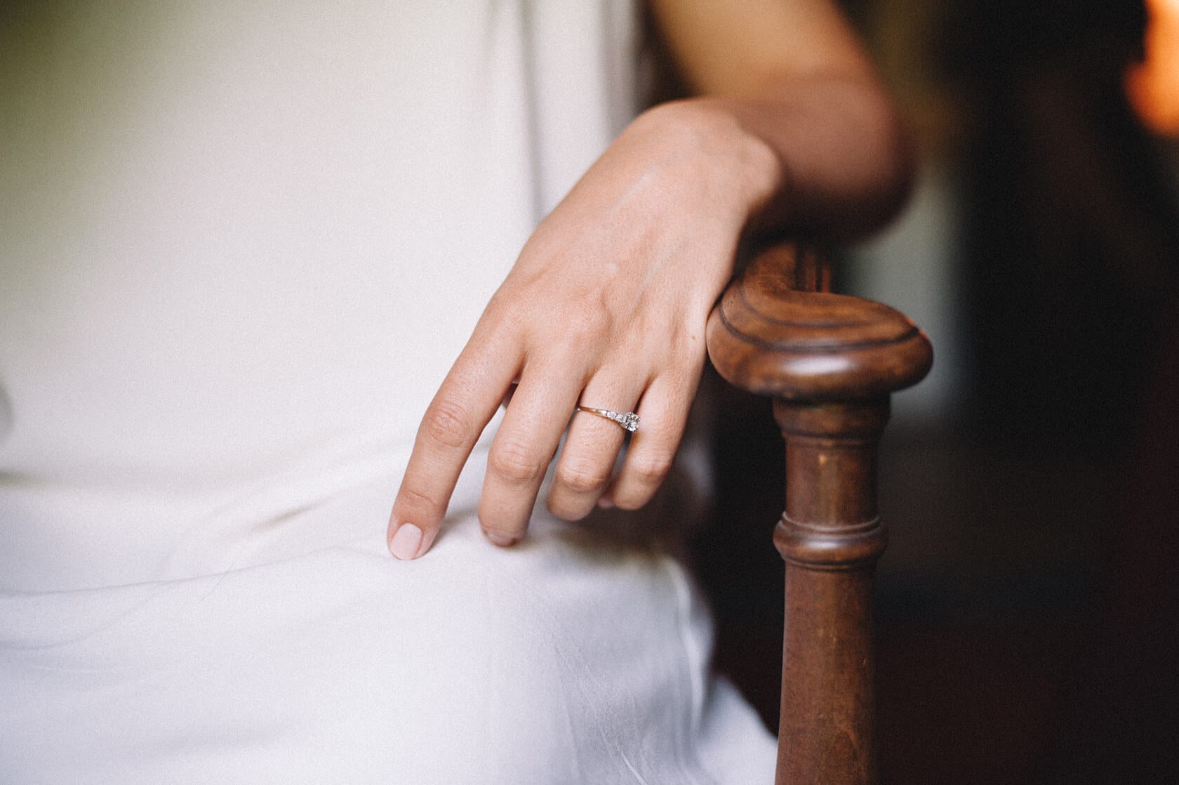 Bride's hand with diamond ring resting on wooden chair arm at Villa Almanita, Sitges - Barcelona Wedding Photographer