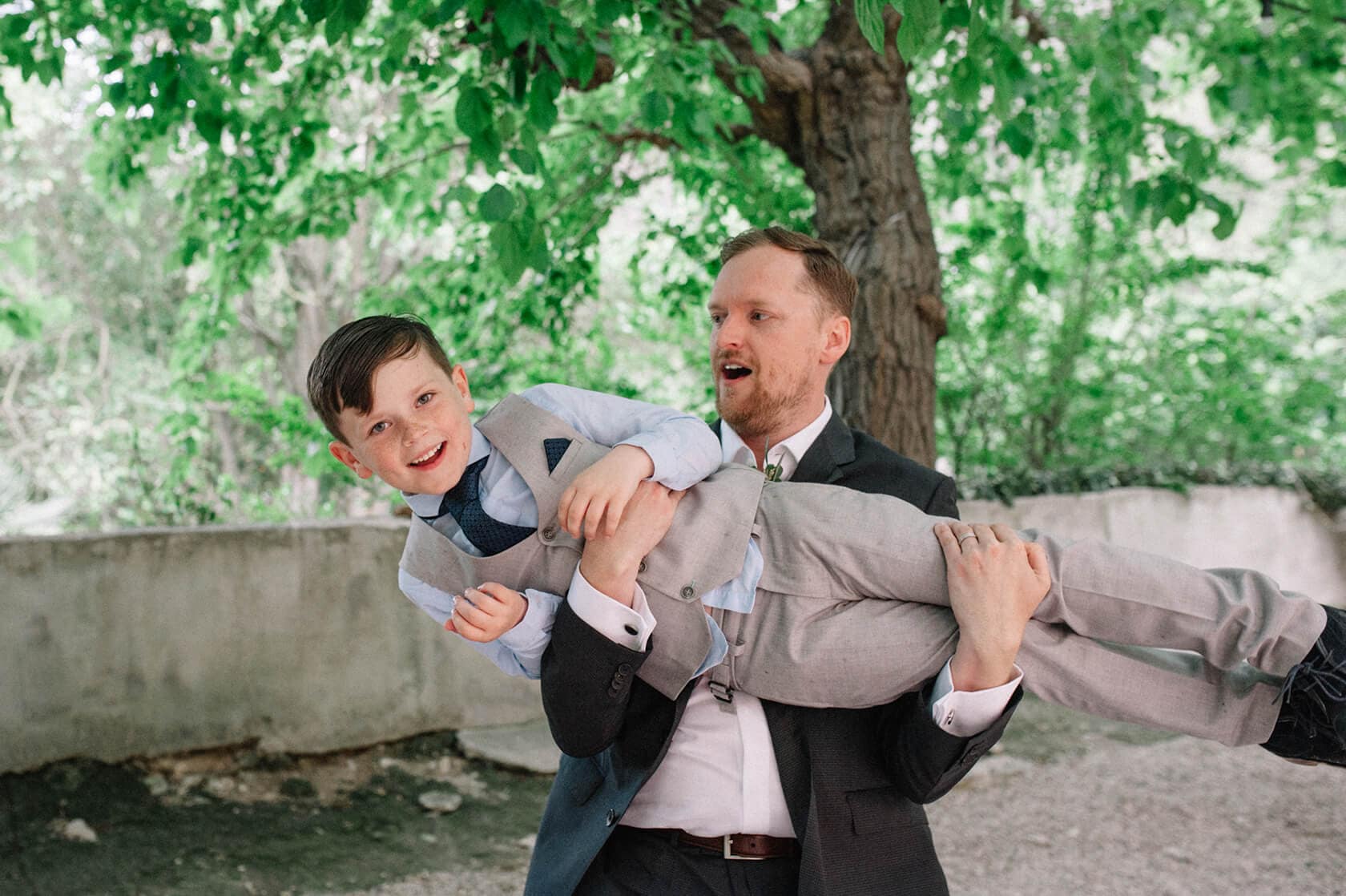 Groom holding a happy ring bearer at a destination wedding in Sitges, Spain. - Barcelona Wedding Photographer