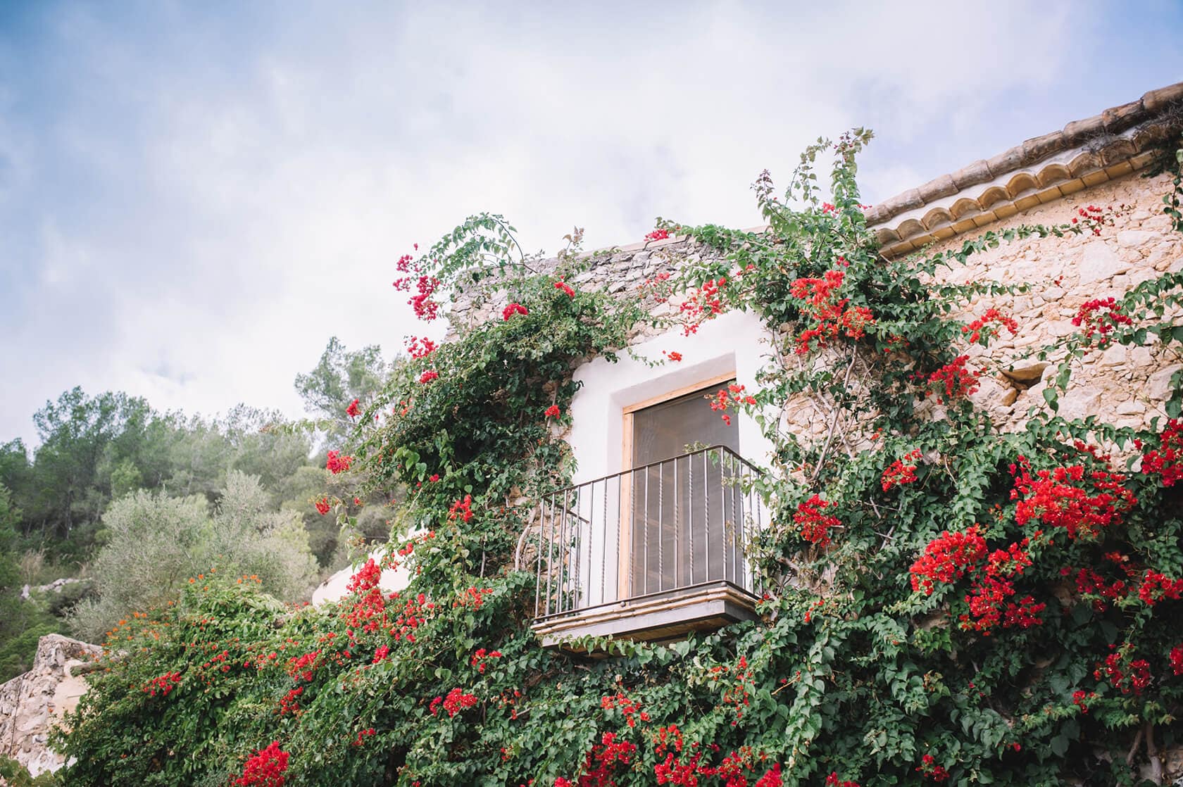 Stone building with balcony draped in red bougainvillea, ideal for Barcelona wedding venues - Barcelona Wedding Photographer