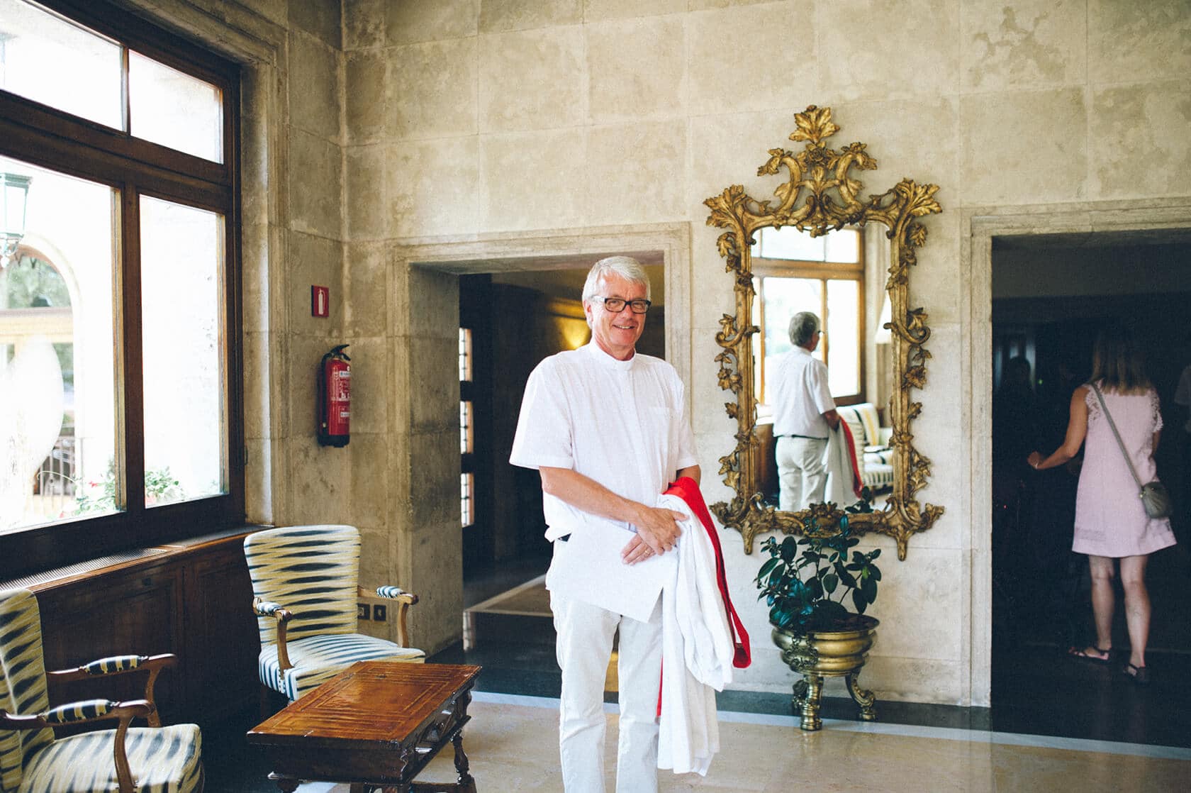 Groom in white holding robe in Spanish wedding venue - Barcelona Wedding Photographer