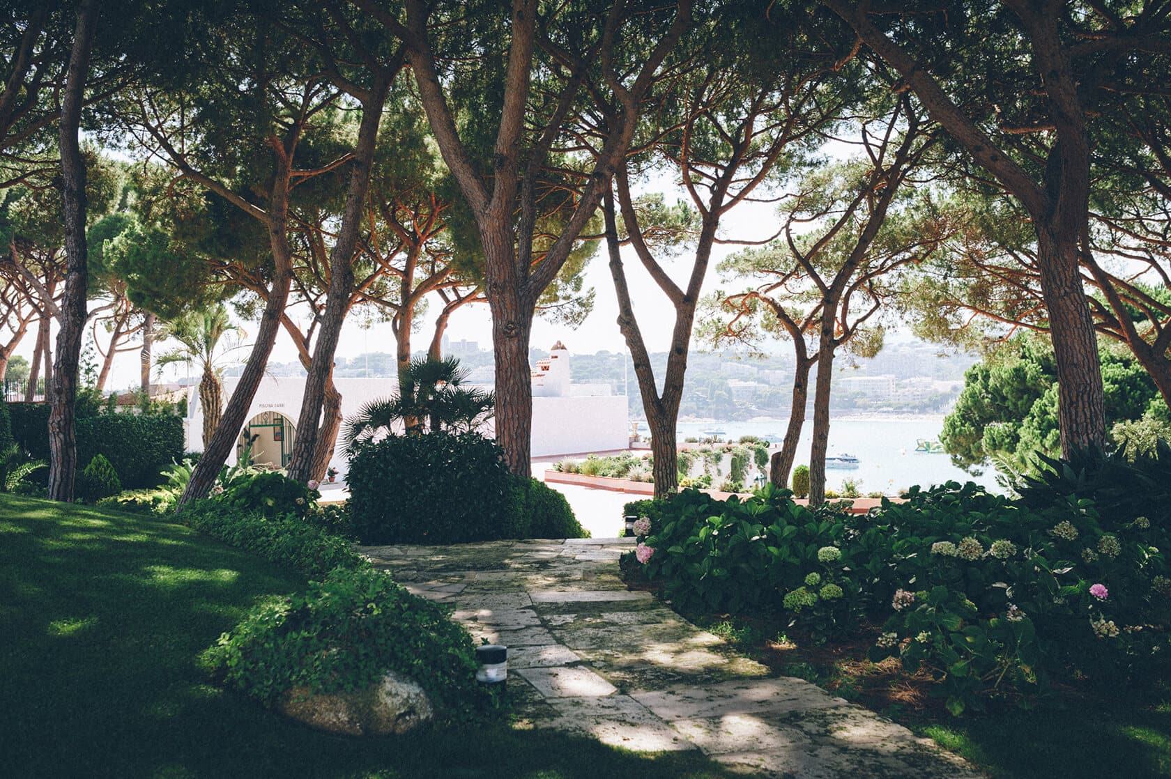 Tsega & Anders wedding in S'Agaro, Spain: pine trees, stone path, and sea view. - Barcelona Wedding Photographer