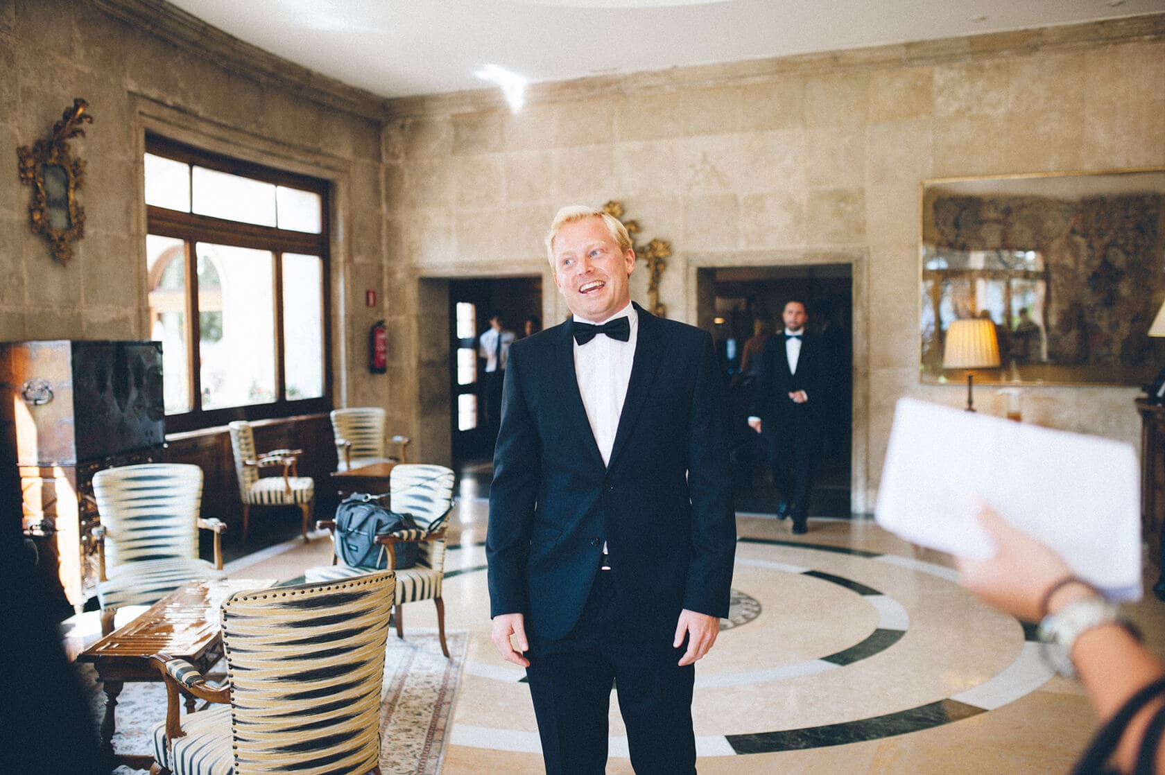 Groom in tuxedo smiles in luxurious hotel lobby, S'Agaro wedding photographer - Barcelona Wedding Photographer
