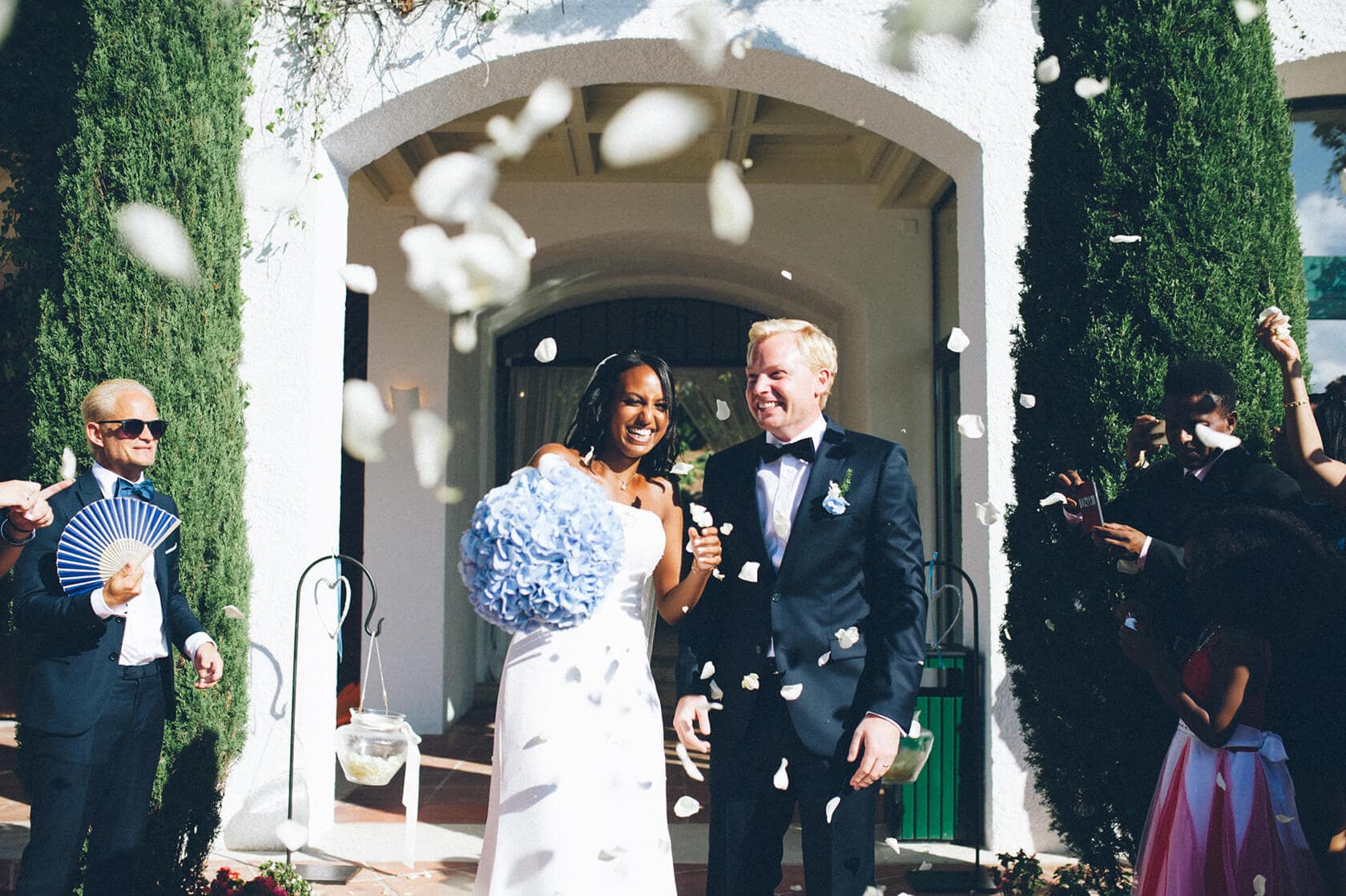 Bride and groom showered with petals by wedding guests in S'Agaro, Spain. - Barcelona Wedding Photographer