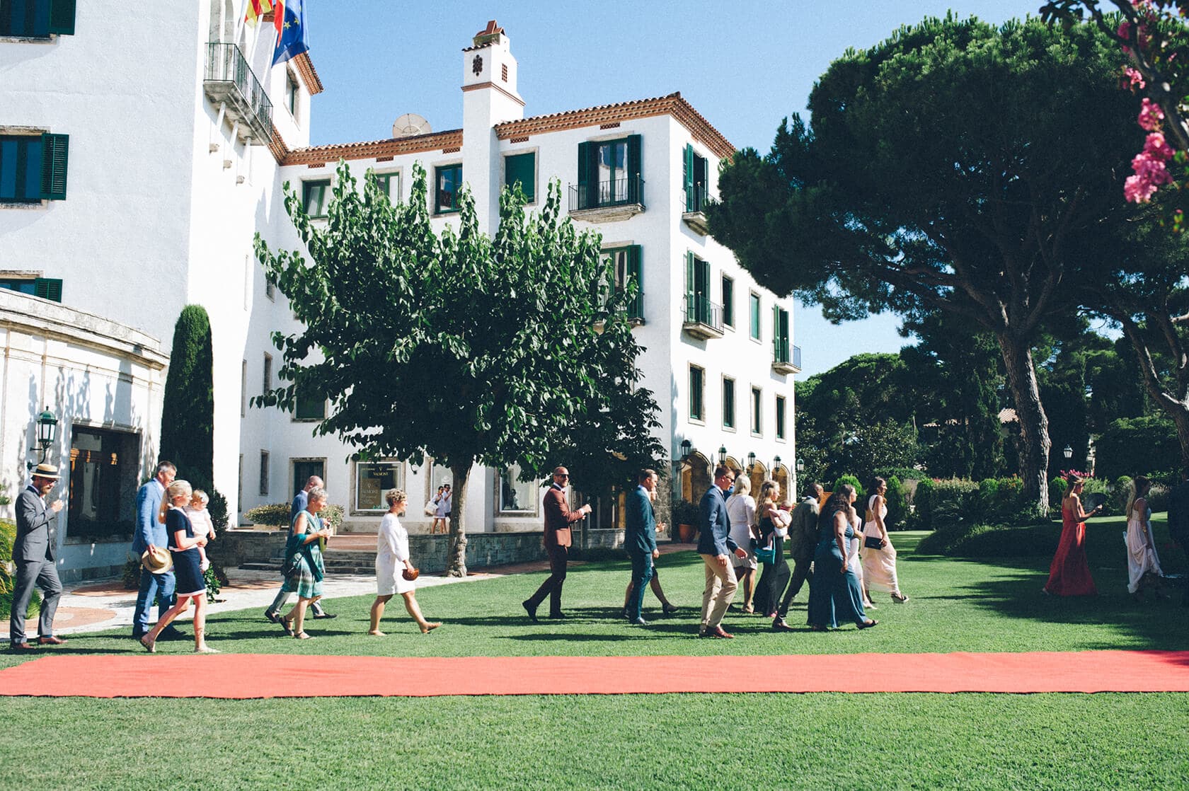 Wedding party walking on red carpet at S'Agaro Spain venue. - Barcelona Wedding Photographer