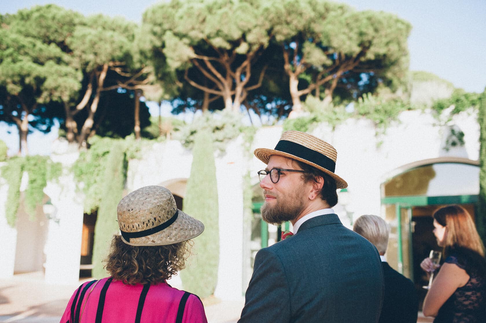 Tsega & Anders' wedding photographer captures guests in stylish hats outdoors in S'Agaro, Spain. - Barcelona Wedding Photographer