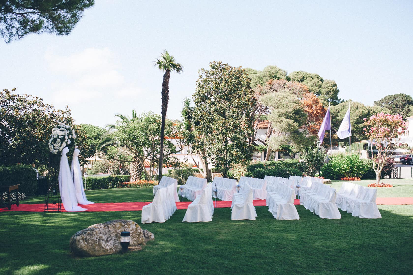 Wedding ceremony setup with white chairs and red carpet in S'Agaro, Spain. - Barcelona Wedding Photographer