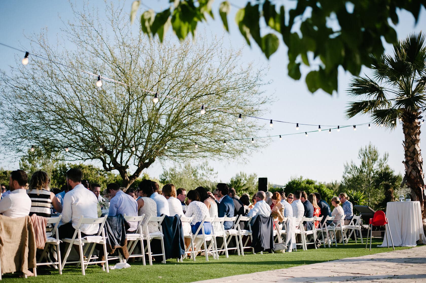 Outdoor wedding reception at Casanova Estate with guests seated at tables under string lights. - Barcelona Wedding Photographer