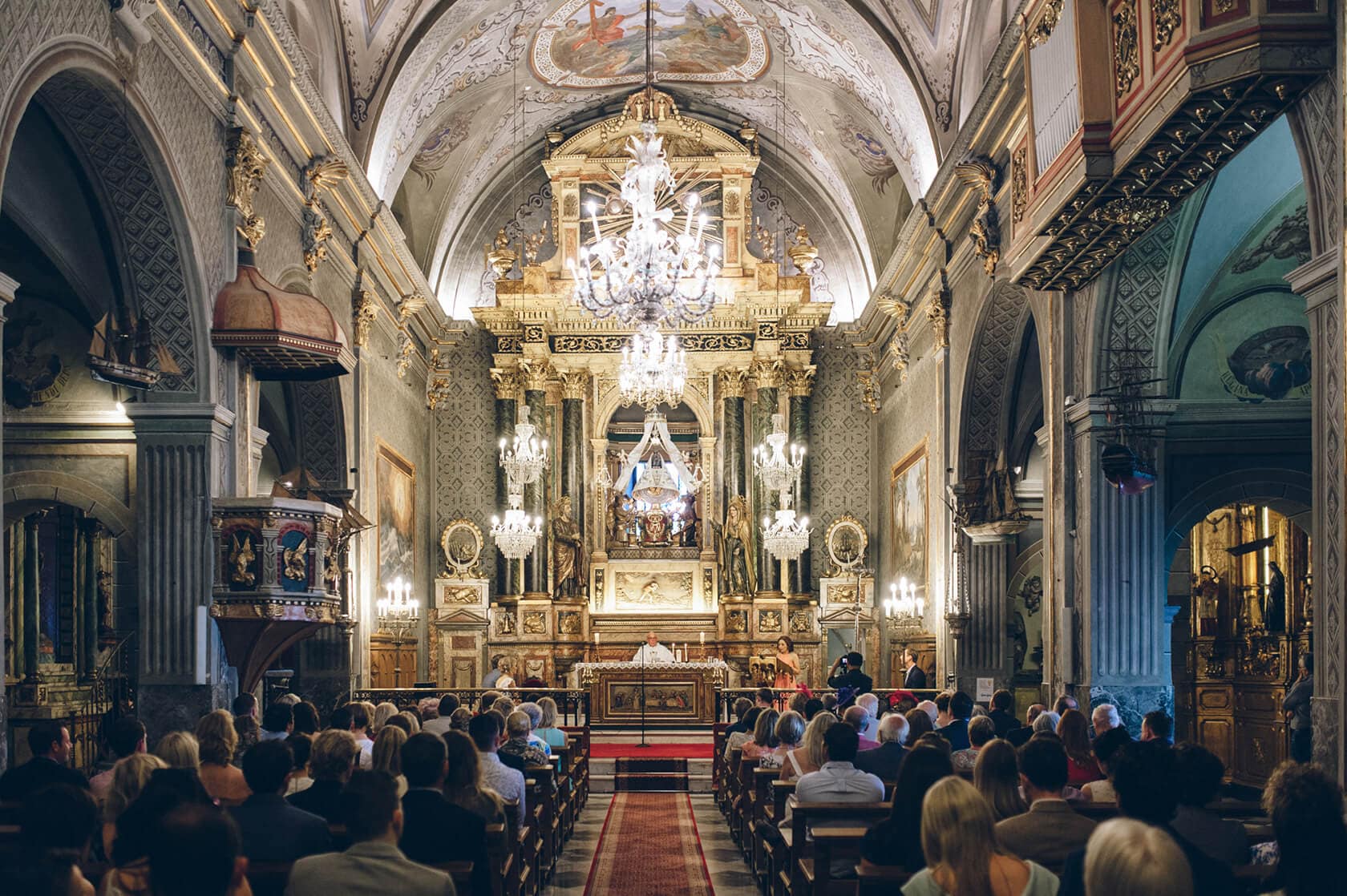 Wedding guests seated in a grand, ornate church, possibly at Casanova Estate. - Barcelona Wedding Photographer