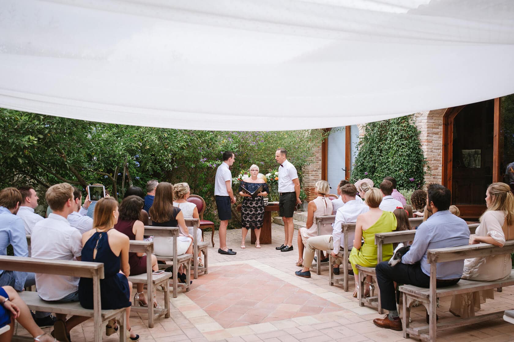 Gay wedding ceremony in Sitges: Adam and Gary exchange vows under a white canopy. - Barcelona Wedding Photographer