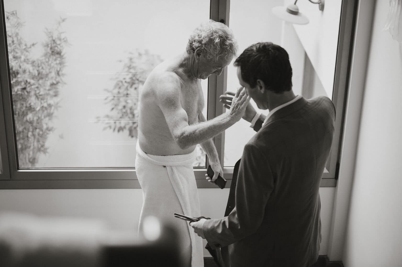 Groom in suit helps father of the bride at Casanova Estate wedding venue. - Barcelona Wedding Photographer