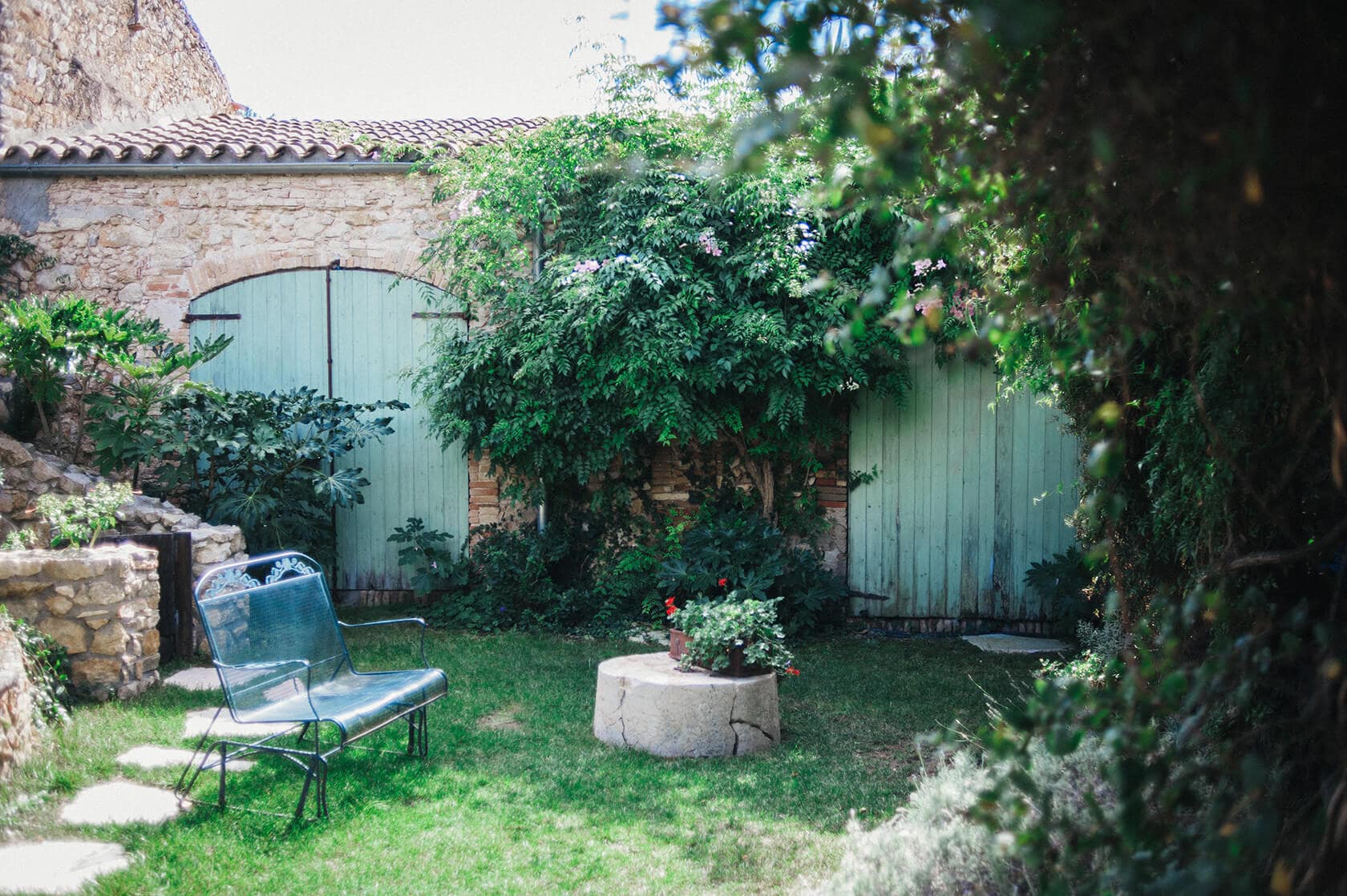 Villas in Sitges Tranquil courtyard garden with a metal chair and vintage wooden doors - Barcelona Wedding Photographer