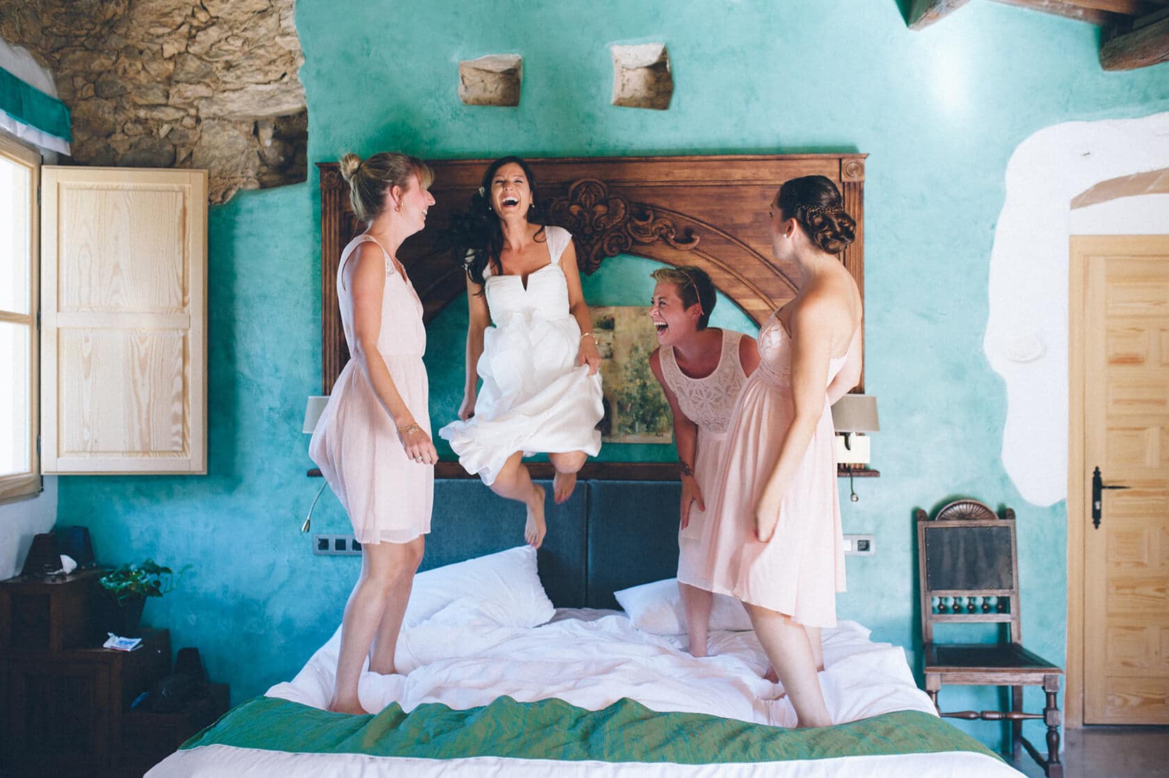 Bridesmaids jumping on a bed in a Sitges wedding villa - Barcelona Wedding Photographer