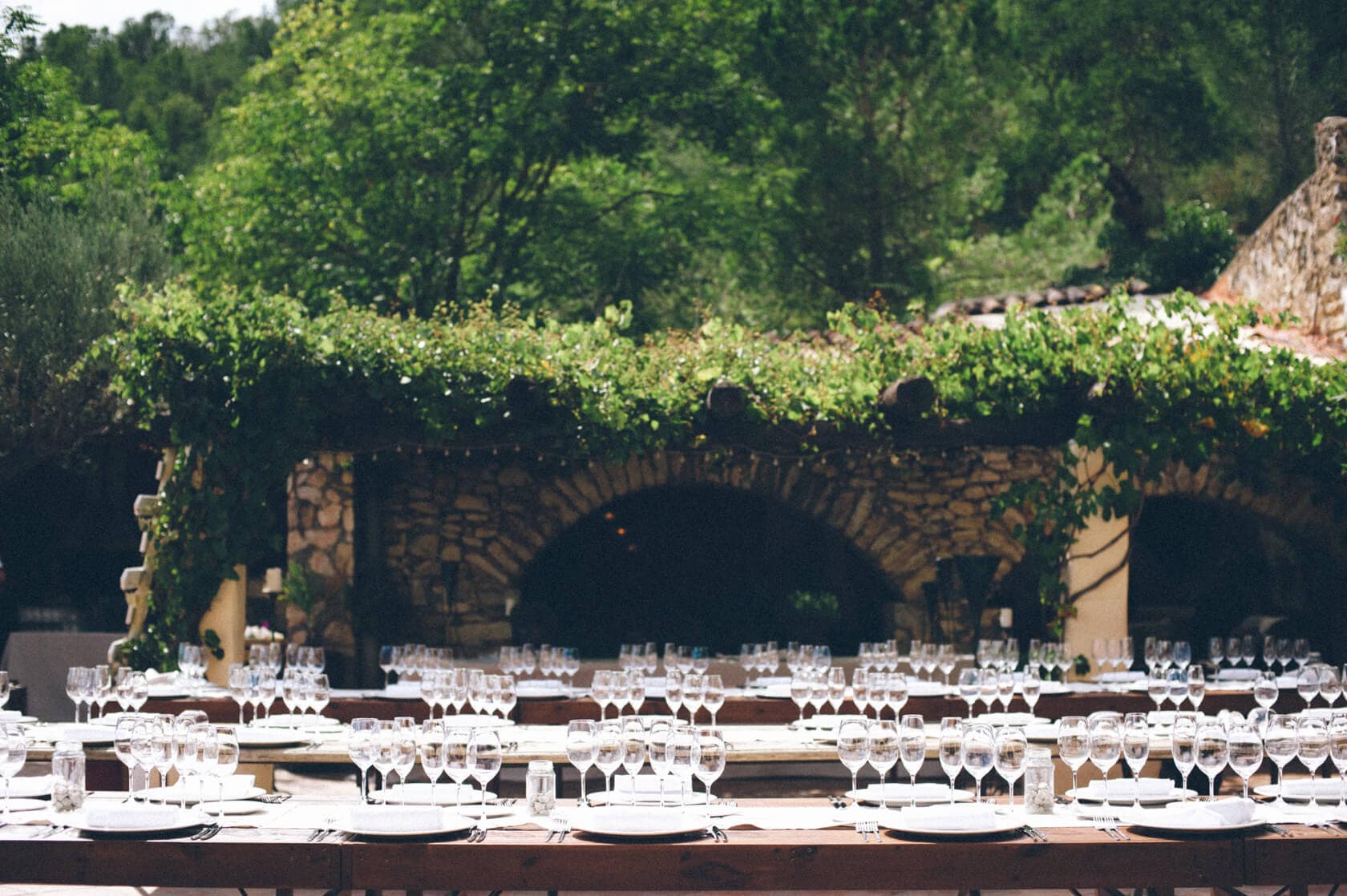 Outdoor wedding reception setup with tables, chairs, and glassware at a villa in Sitges. - Barcelona Wedding Photographer