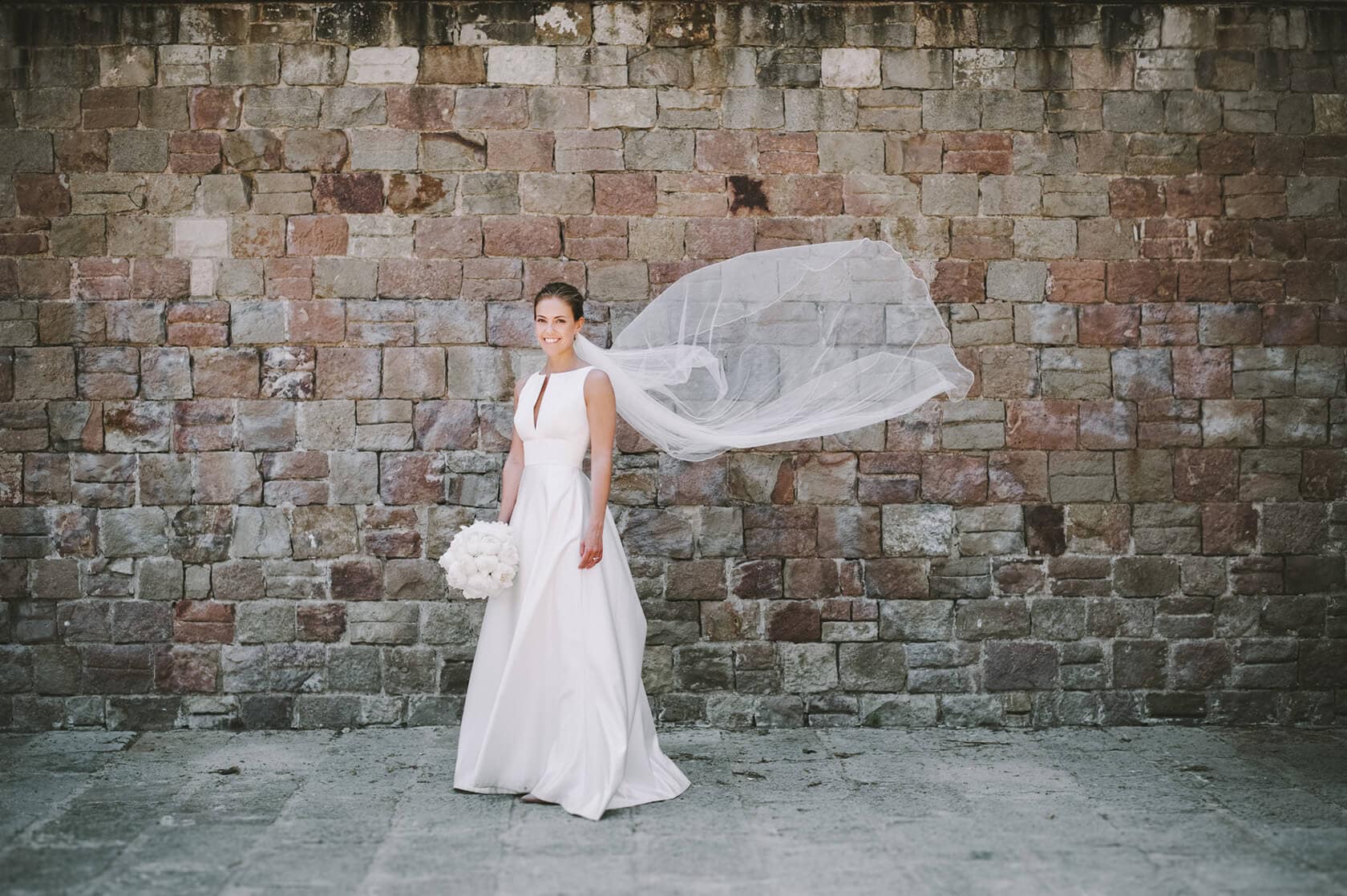 Bride at Hotel Miramar Barcelona wedding, holding bouquet, veil blowing - Barcelona Wedding Photographer