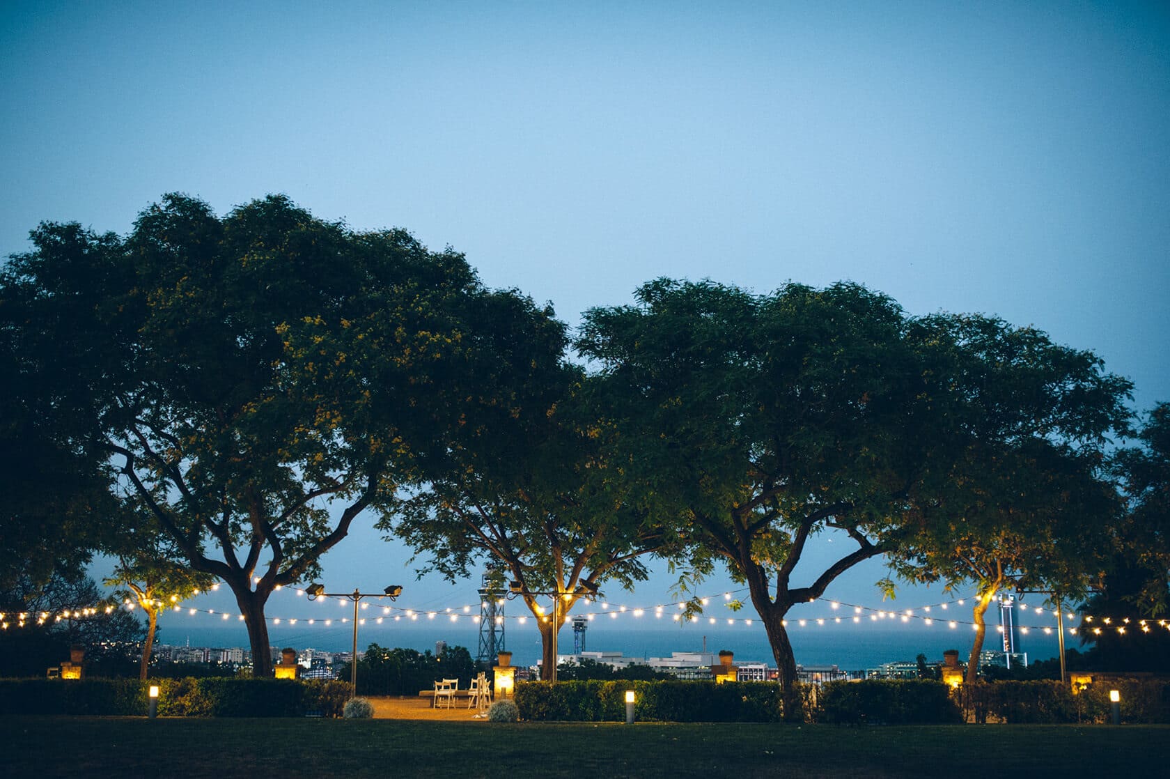 Hotel Miramar Barcelona wedding setup with trees and string lights at dusk - Barcelona Wedding Photographer