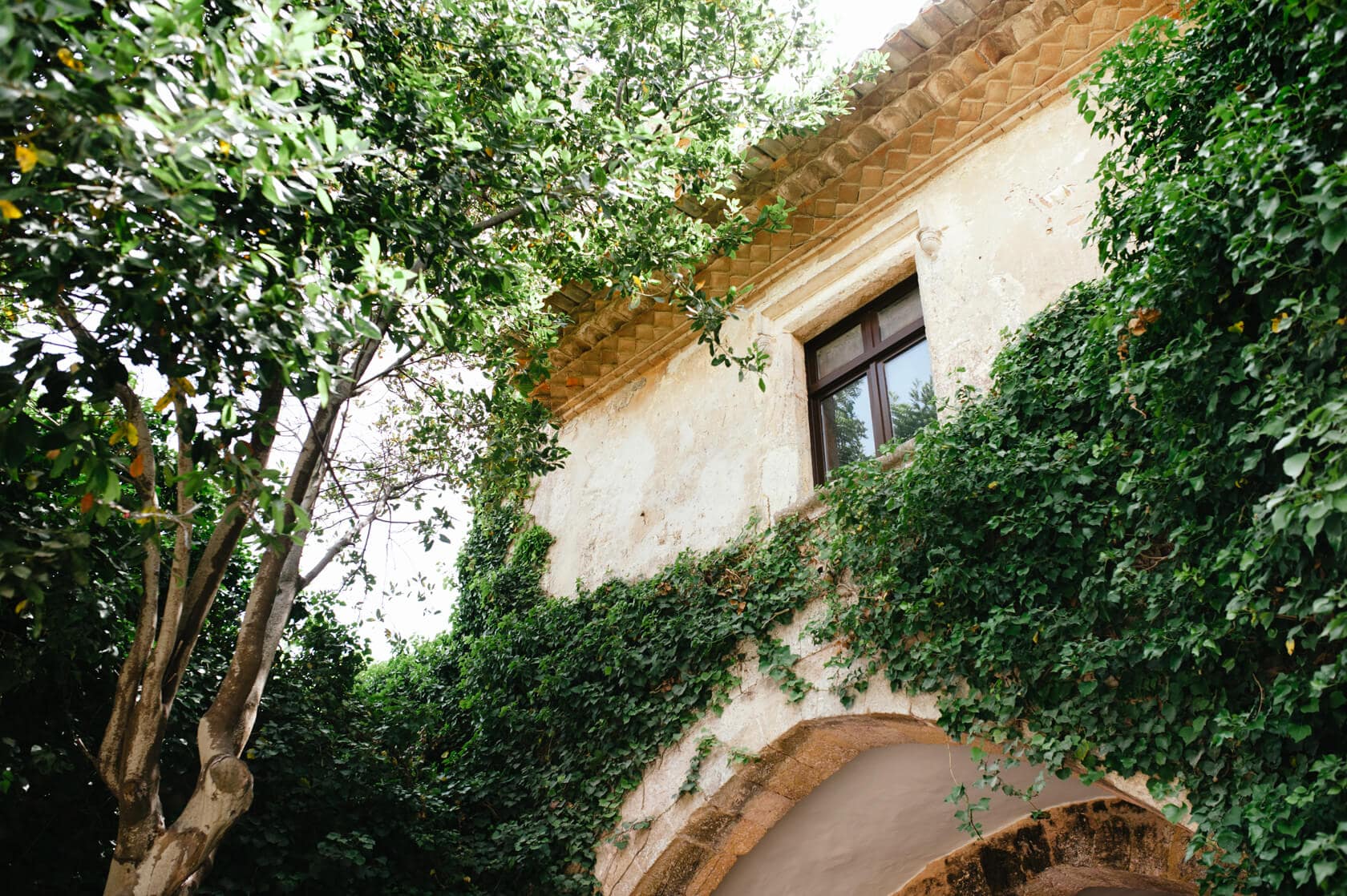 Castell de Tamarit wedding: Ivy-covered stone building with arched entrance - Barcelona Wedding Photographer
