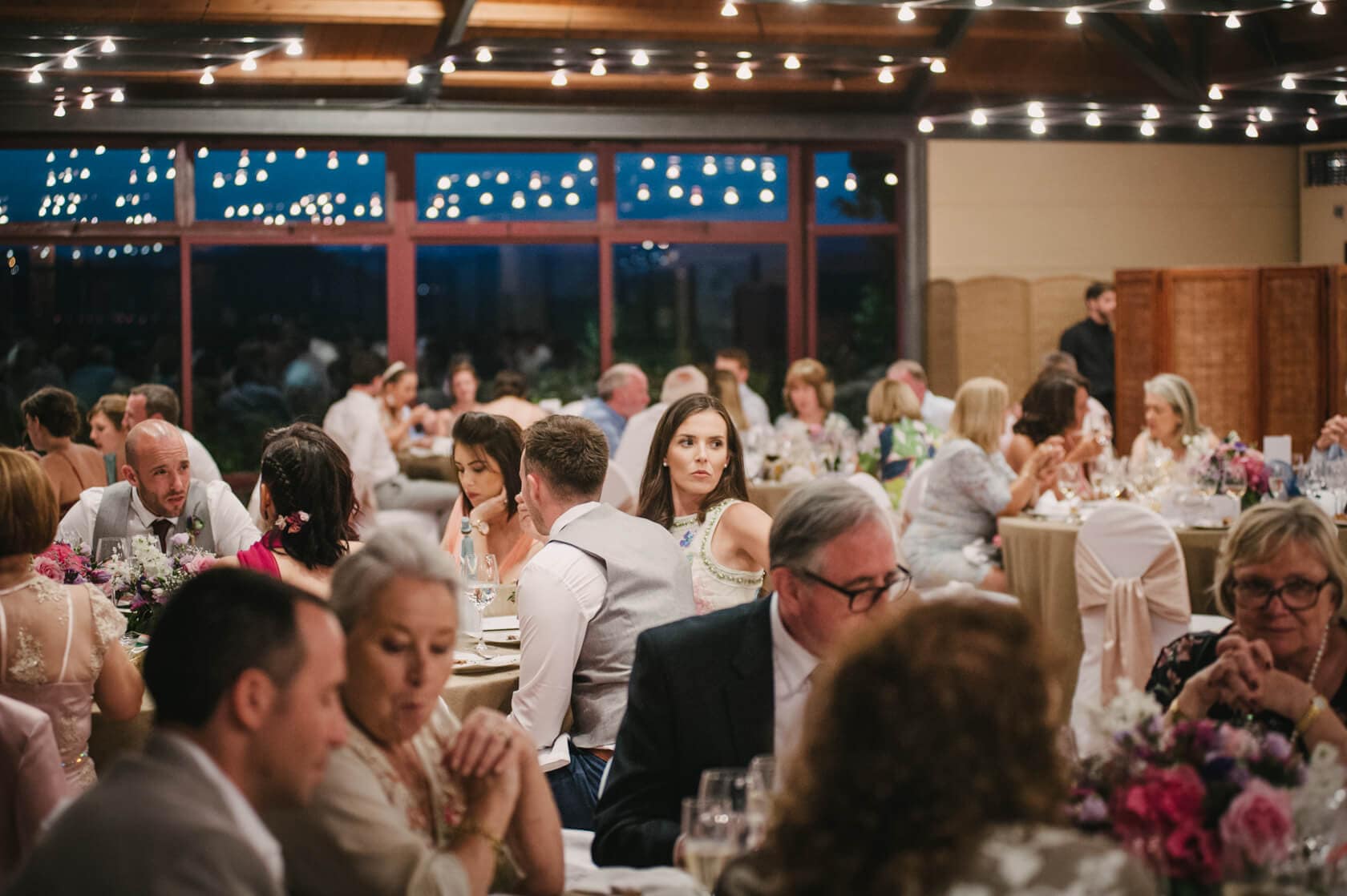 Wedding reception at Castell de Tamarit, Sitges, with guests dining under string lights. - Barcelona Wedding Photographer