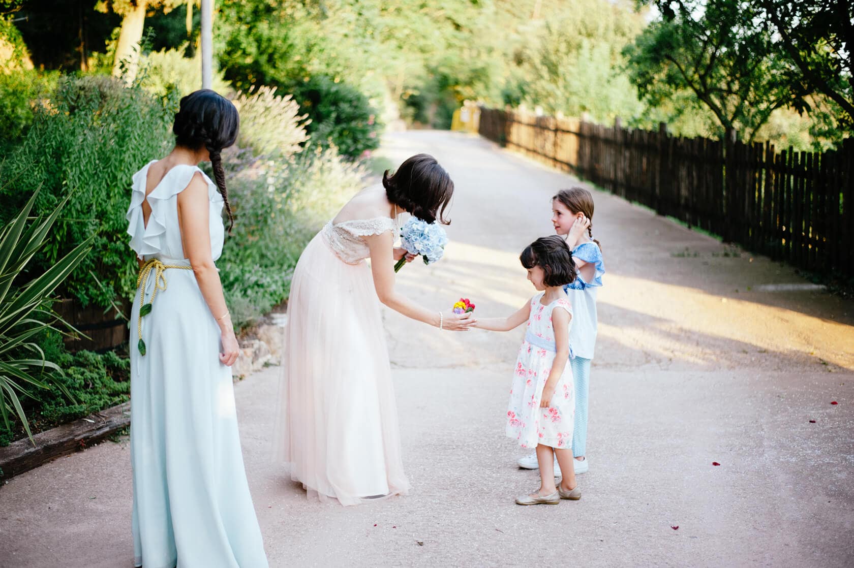 Bride in vintage style wedding dress gives flowers to flower girls. - Barcelona Wedding Photographer