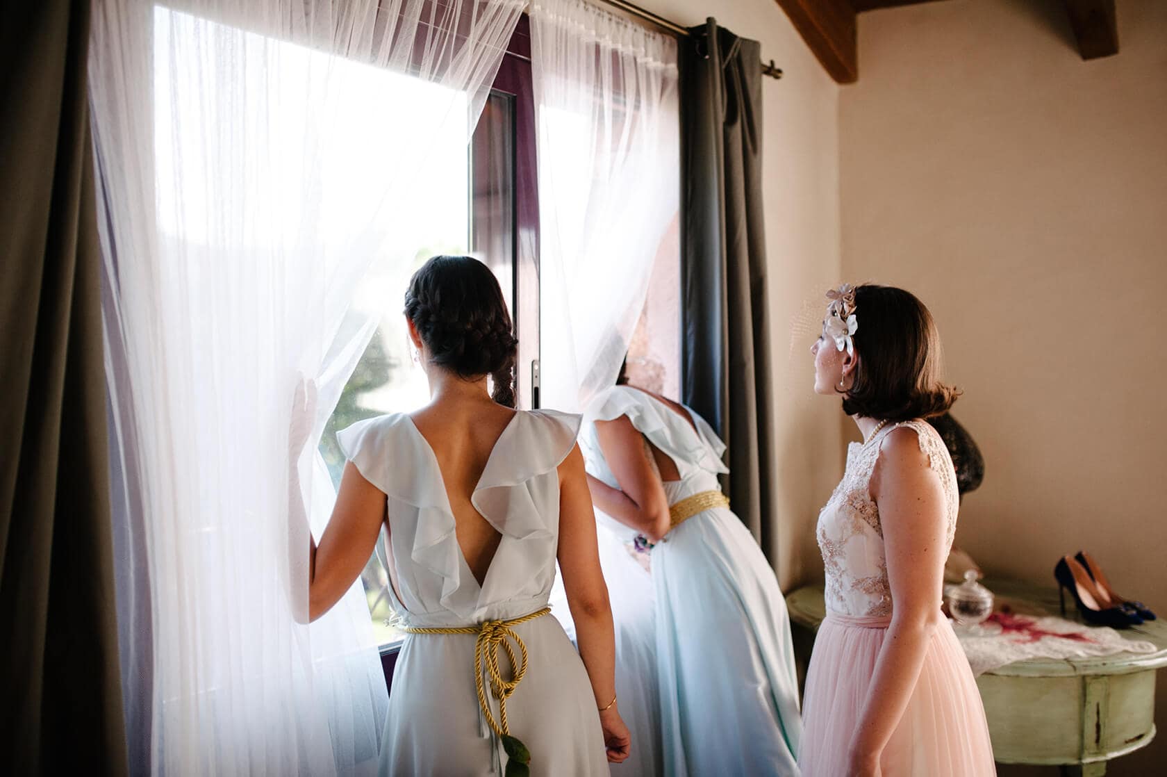 Bridesmaids in vintage style wedding dresses look out window - Barcelona Wedding Photographer