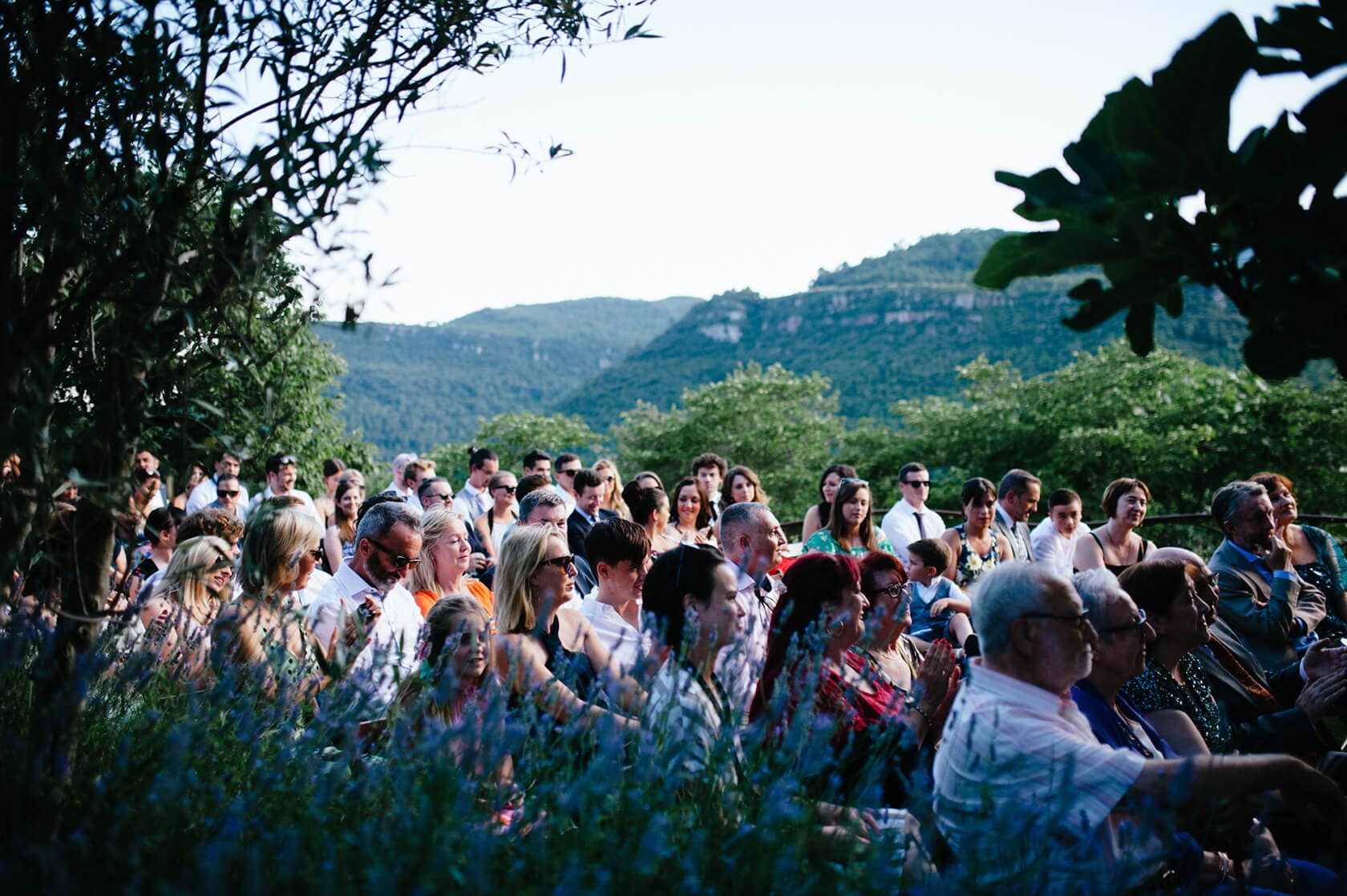 Guests at a vintage style wedding ceremony outdoors with mountains in the background - Barcelona Wedding Photographer