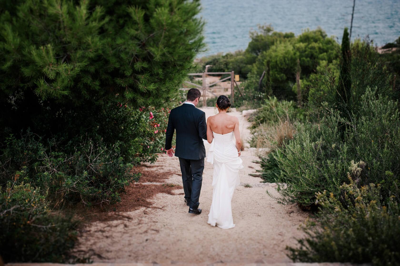 Hayley and Mark, a bride and groom, walk hand-in-hand at their wedding. - Barcelona Wedding Photographer