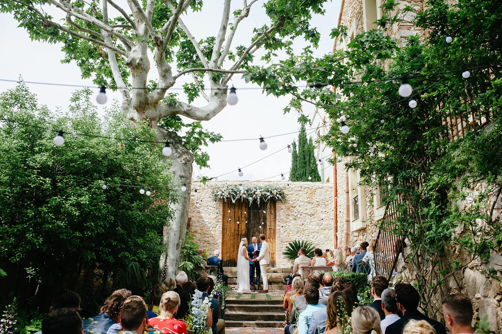 Newlywed couple in wedding attire on a sandy beach with ocean backdrop - Barcelona Wedding Photographer