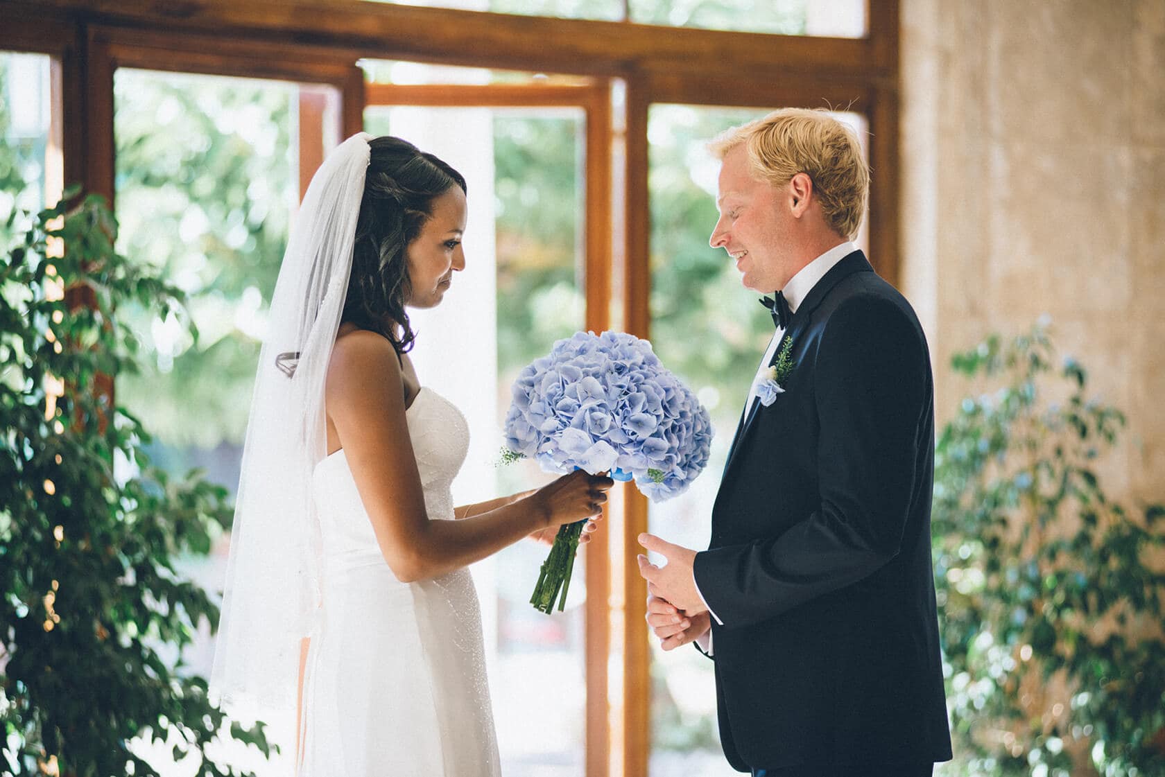 Bride presents blue bouquet to groom during wedding ceremony in S'Agaro, Spain. - Barcelona Wedding Photographer