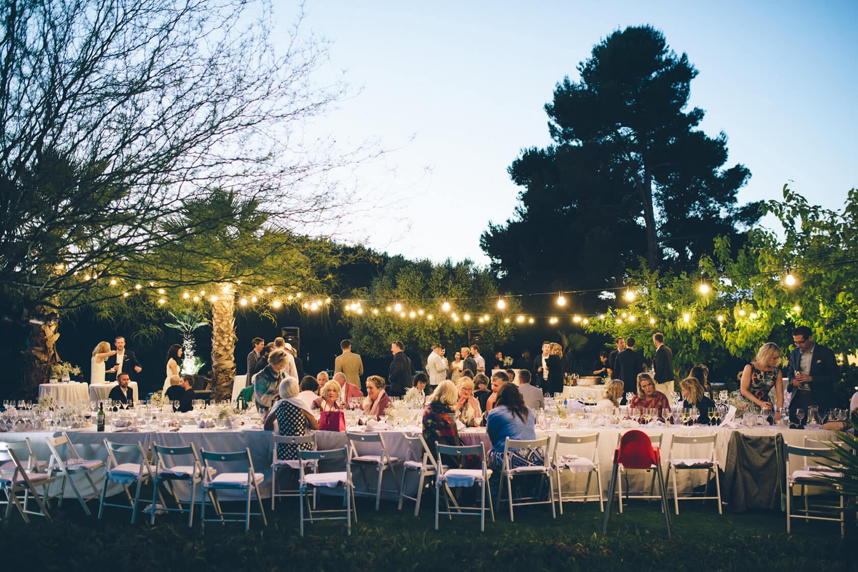 Outdoor wedding reception in Sitges with guests dining under string lights - Barcelona Wedding Photographer