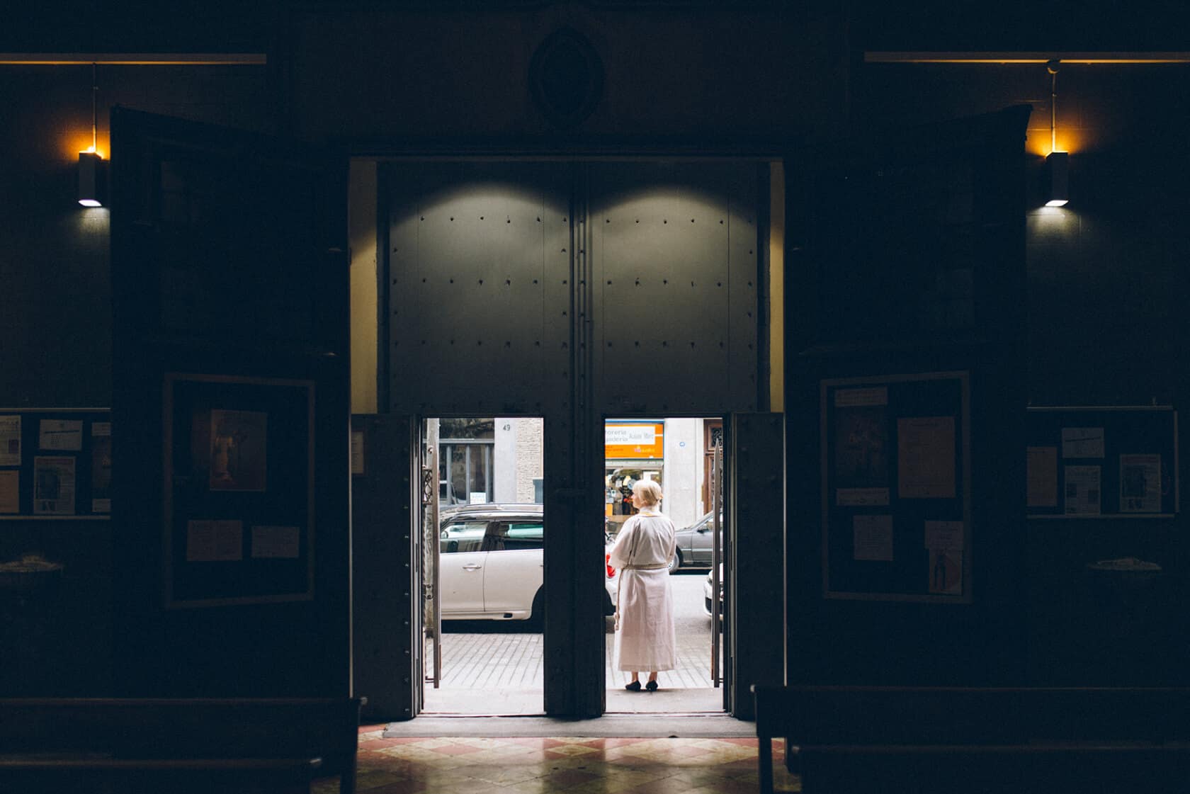 Woman in a white robe stands in a church doorway, Barcelona wedding photographer - Barcelona Wedding Photographer