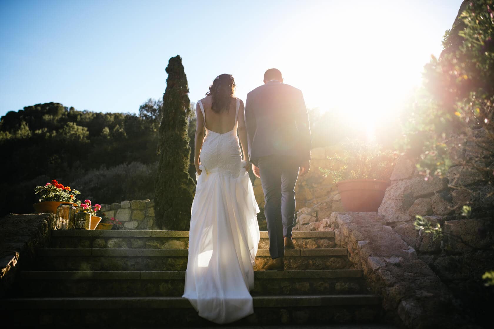 Bride and groom ascend stone steps at Castell de Tamarit wedding, Sitges. - Barcelona Wedding Photographer