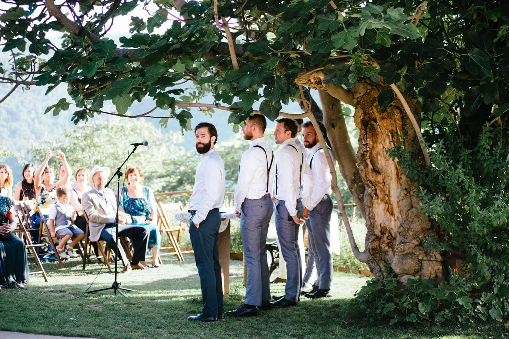 Groomsmen in a vintage style wedding ceremony under a large tree - Barcelona Wedding Photographer