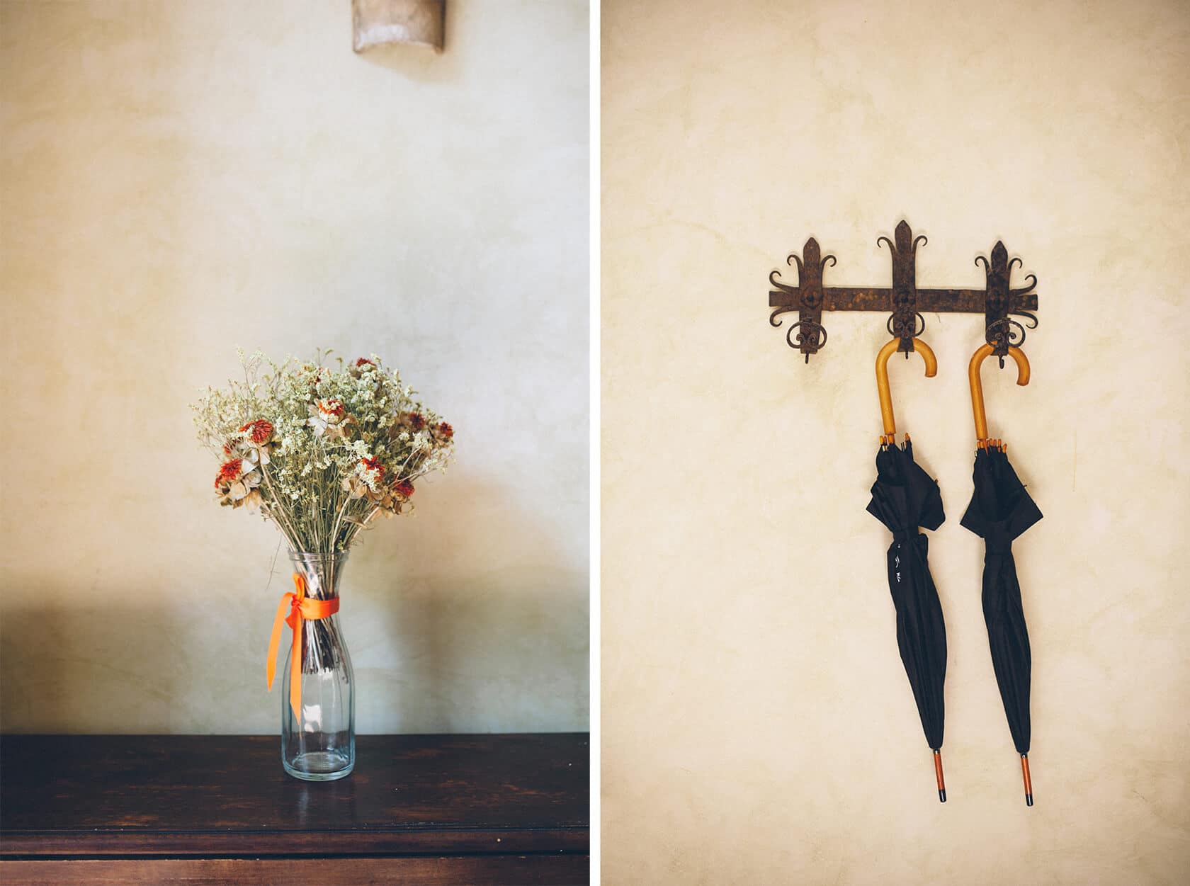 Dried floral arrangement in a glass vase and black umbrellas on a wall hook in a Sitges wedding villa. - Barcelona Wedding Photographer