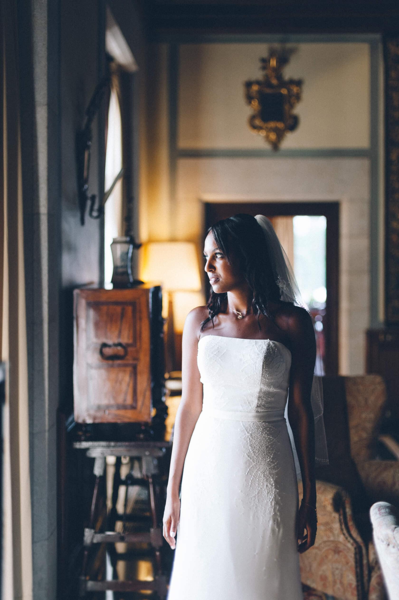 Bride in white strapless wedding dress looking out window, S'Agaro Spain - Barcelona Wedding Photographer