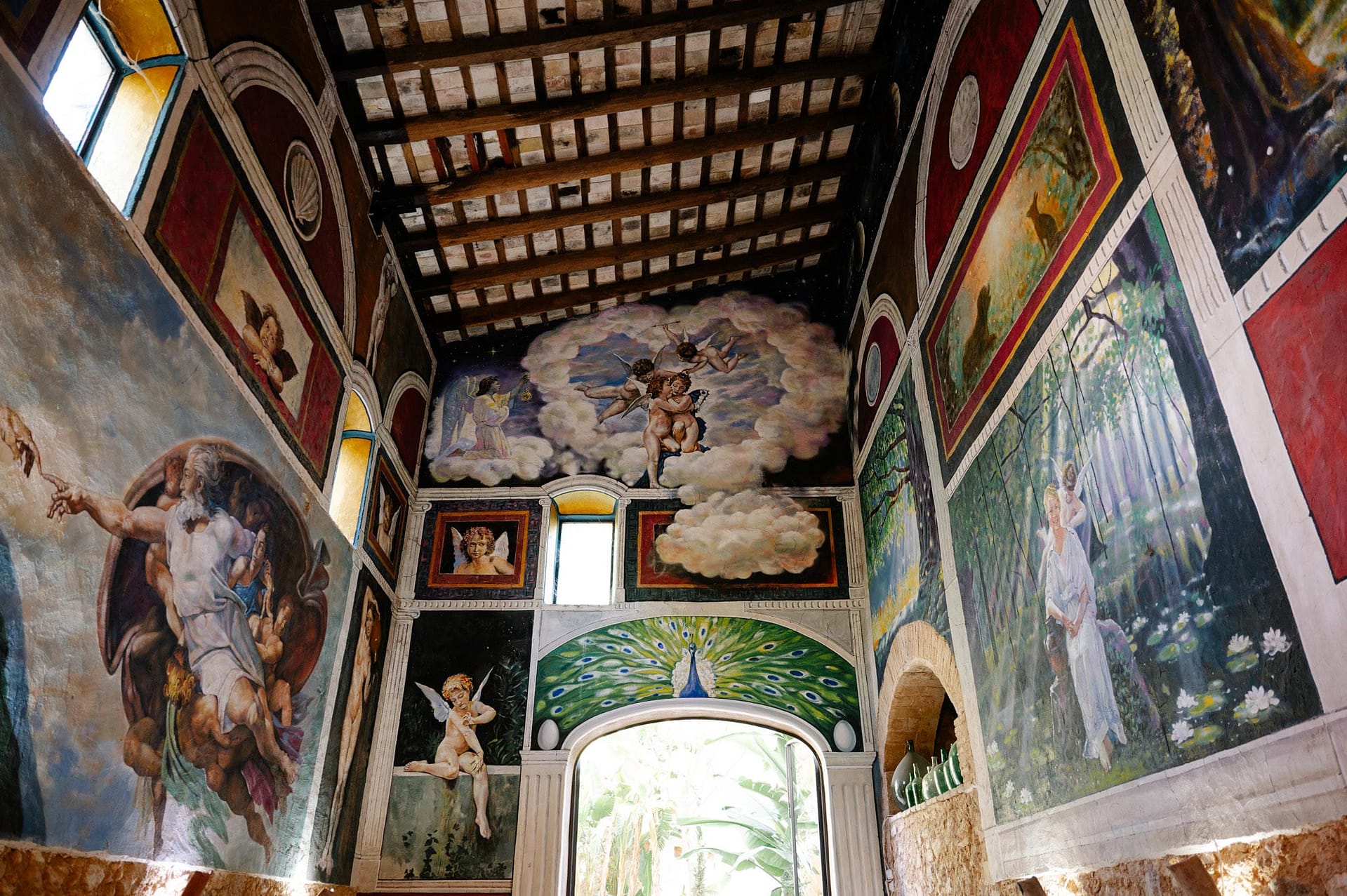 Masia Victoria Vibrant murals adorn the walls of a historic building, featuring cherubs, a peacock, and biblical scenes. - Sitges Wedding Photographer