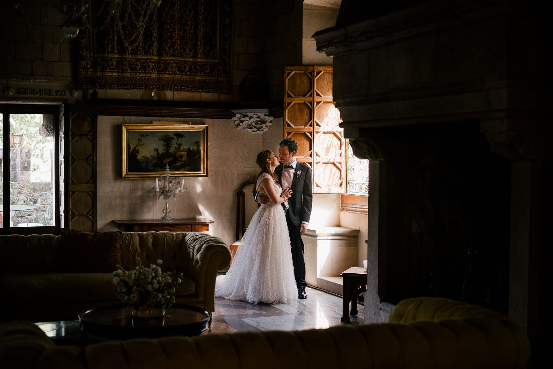 Bride and groom kiss in a dimly lit, opulent room with a fireplace and ornate furniture. - Barcelona Wedding Venues